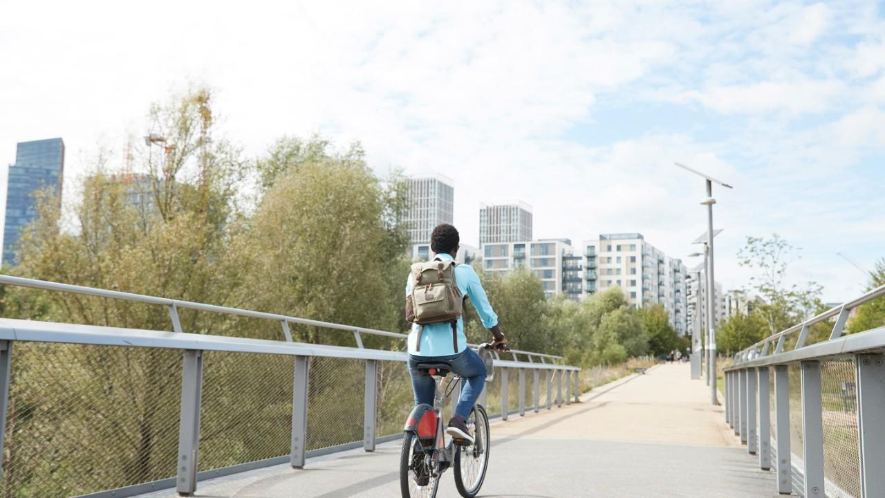 女孩骑着自行车穿过一座桥来到一座城市.